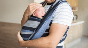 A man holding a baby in a baby carrier.