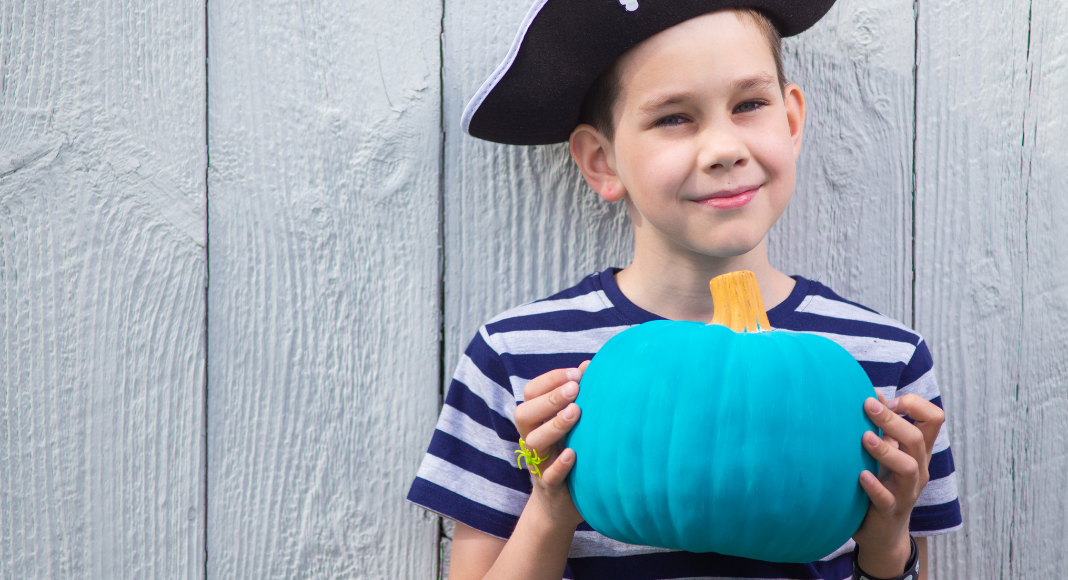 A boy holding a teal pumpkin.