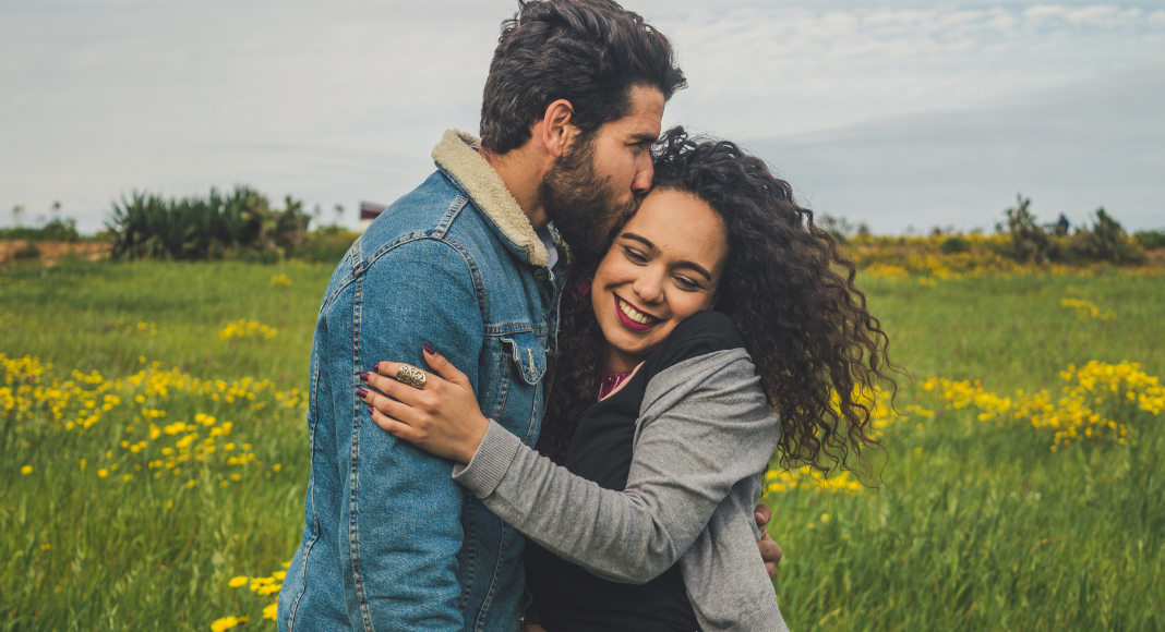 A couple embracing in a field.