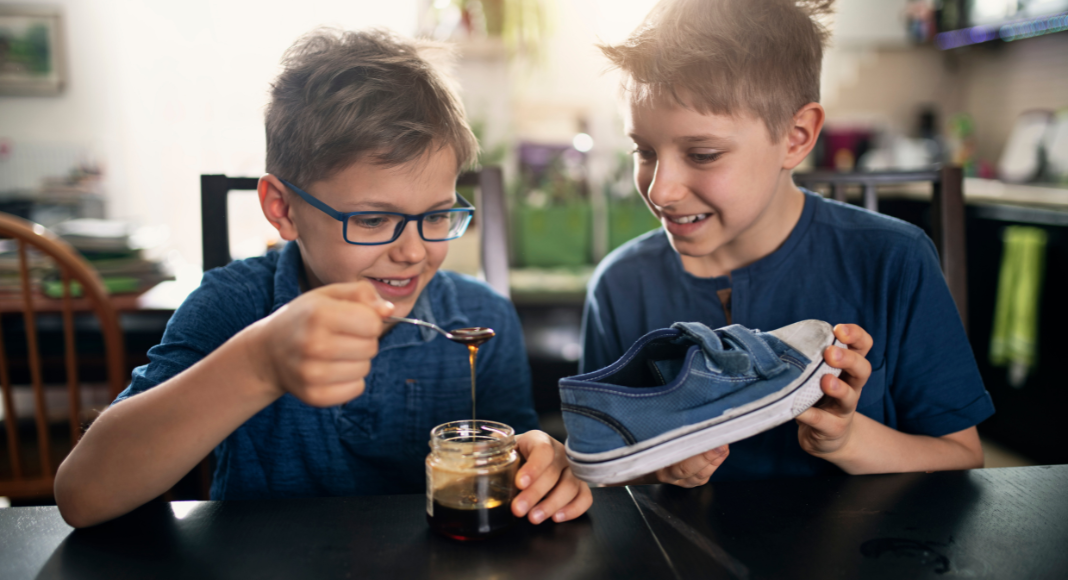 Kids putting honey into a shoe for an April Fools' trick.