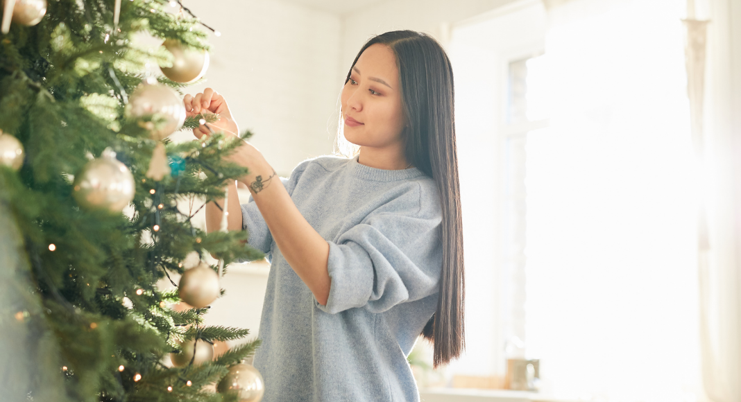 A woman decorating a Christmas tree. 