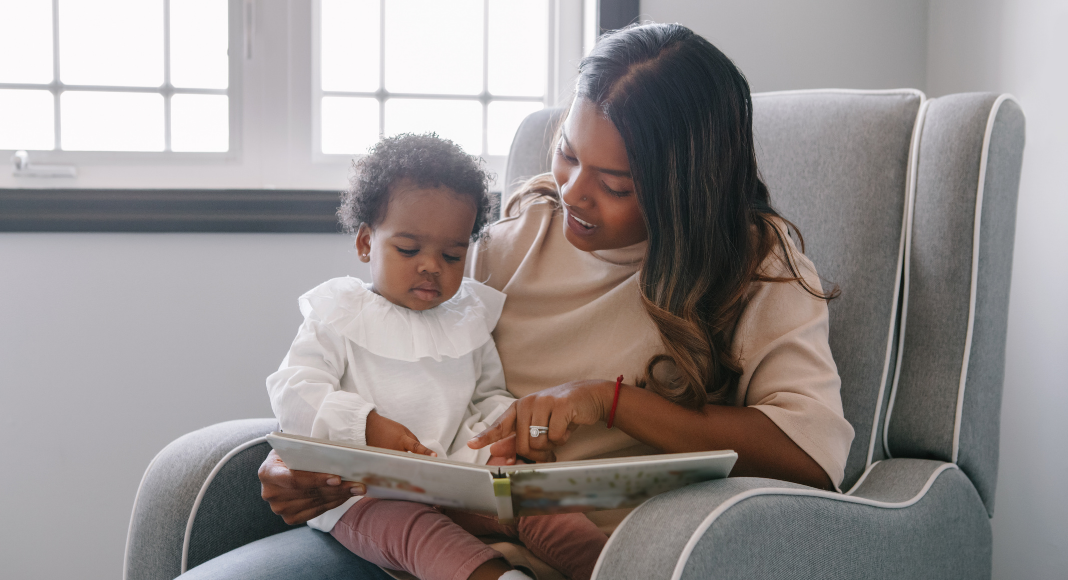 A mom reading a book to a baby.