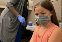 A masked girl about to get her COVID vaccine.