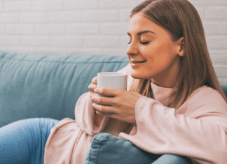 A woman sitting on the couch drinking coffee.