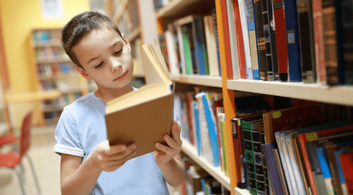 A boy reading a book in the library.
