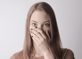 A quiet woman covering her mouth with her hand.