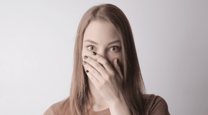A quiet woman covering her mouth with her hand.
