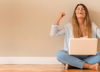 A woman cheering on a computer.