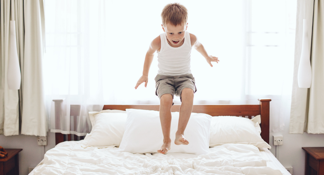 A boy jumping on the bed.