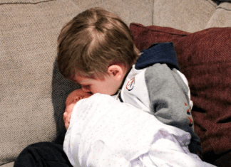 A big brother kissing his baby sister.