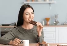 A woman eating chocolate and drinking coffee.