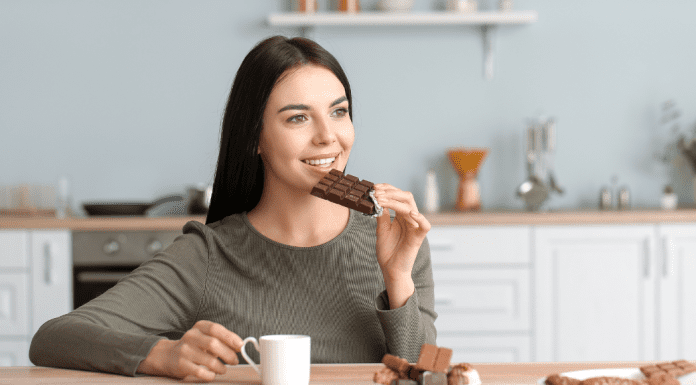 A woman eating chocolate and drinking coffee.