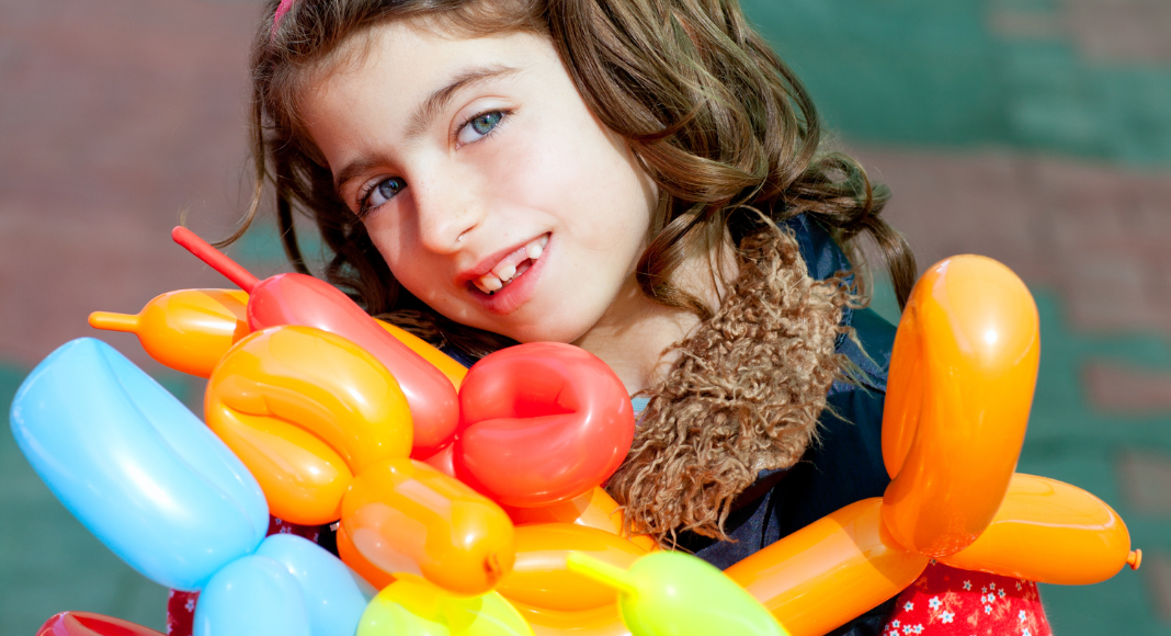 A girl holding a bunch of balloon animals.