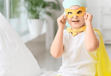A child with cancer dressed in a mask and yellow cape.