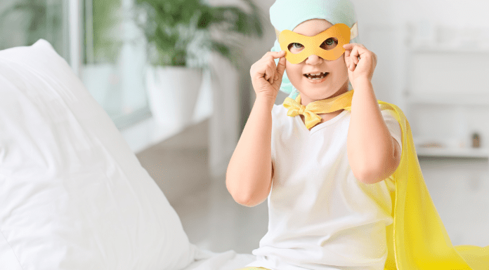 A child with cancer dressed in a mask and yellow cape.