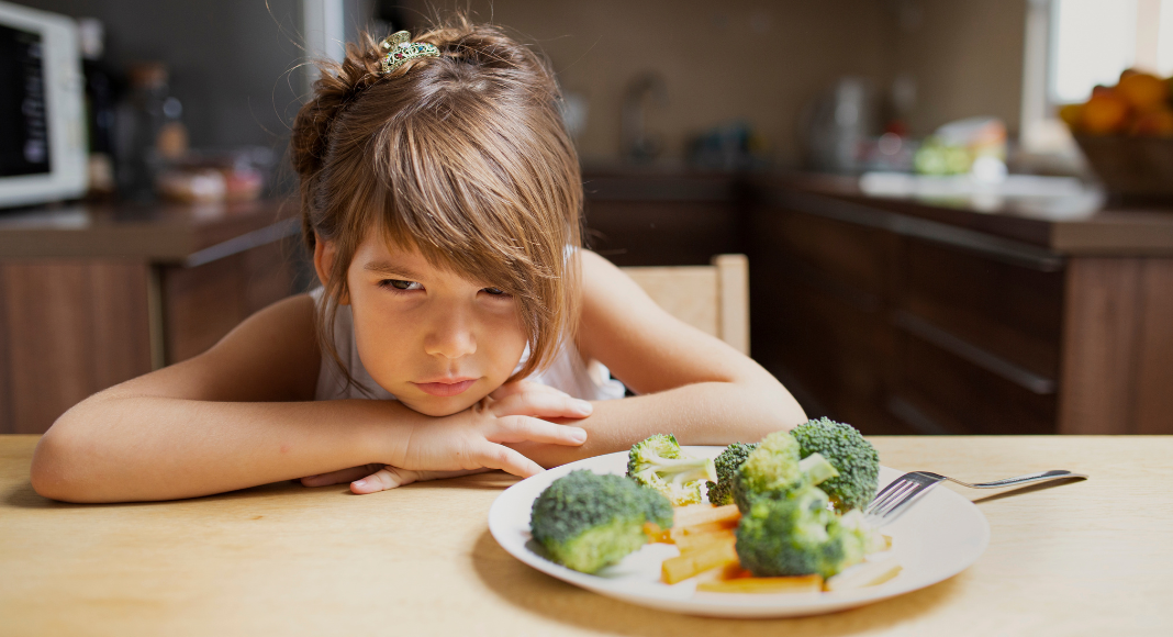 A girl refusing to eat her vegetables.