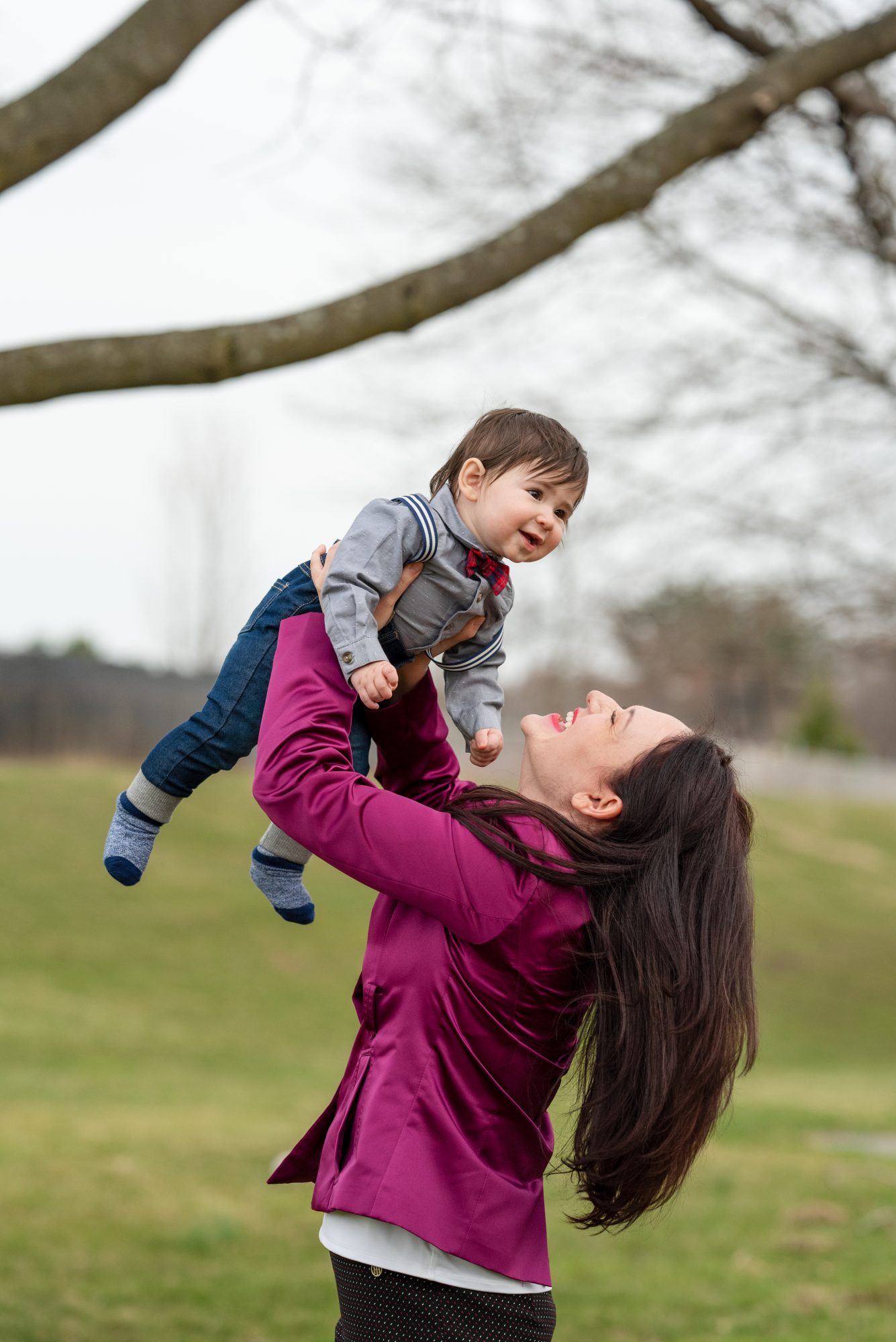 A woman holding her son in the air.