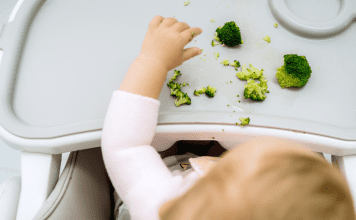 A baby eating broccoli.